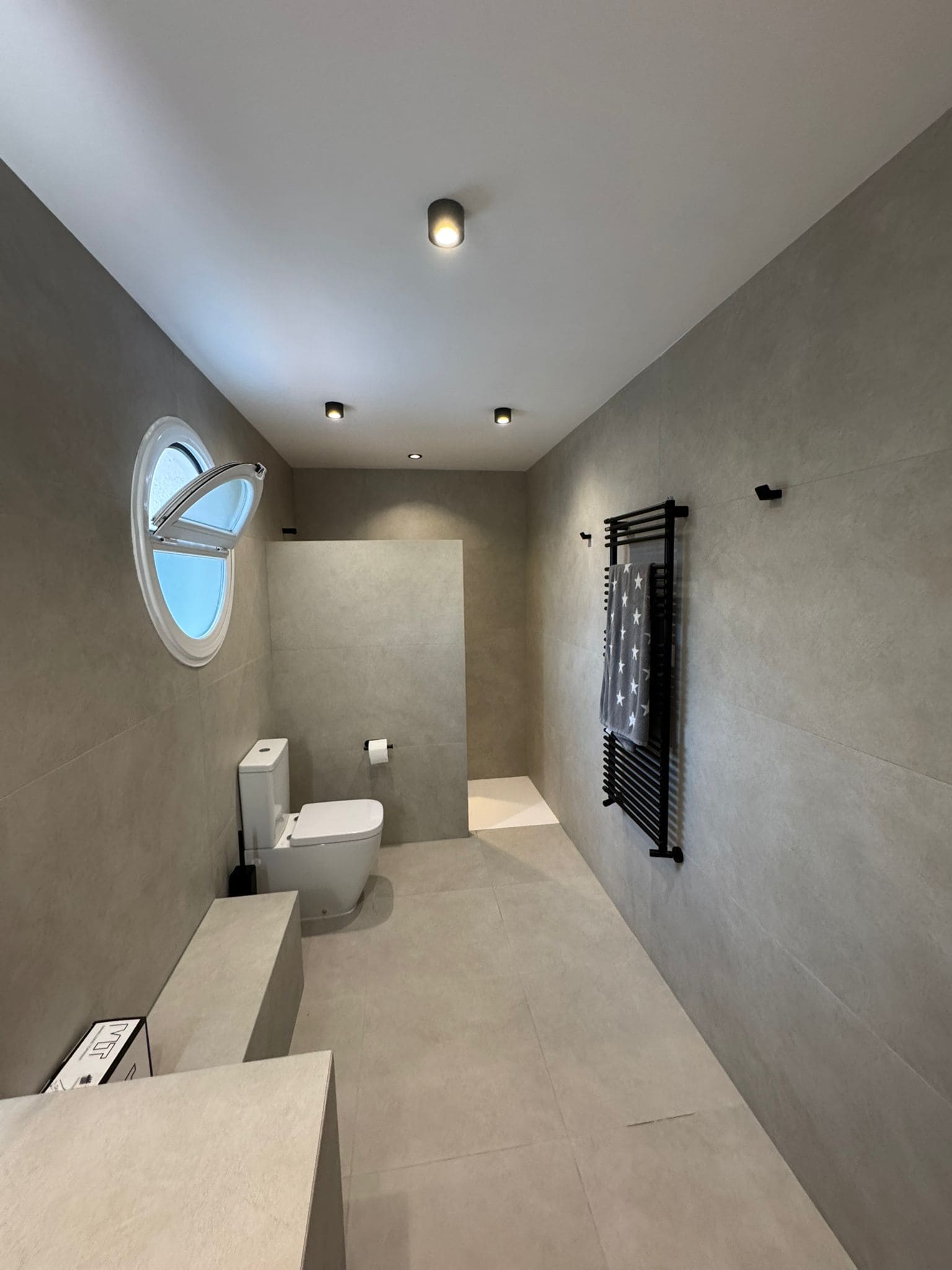Reforma integral de baño moderno realizada por Masmel con acabados en porcelánico gris